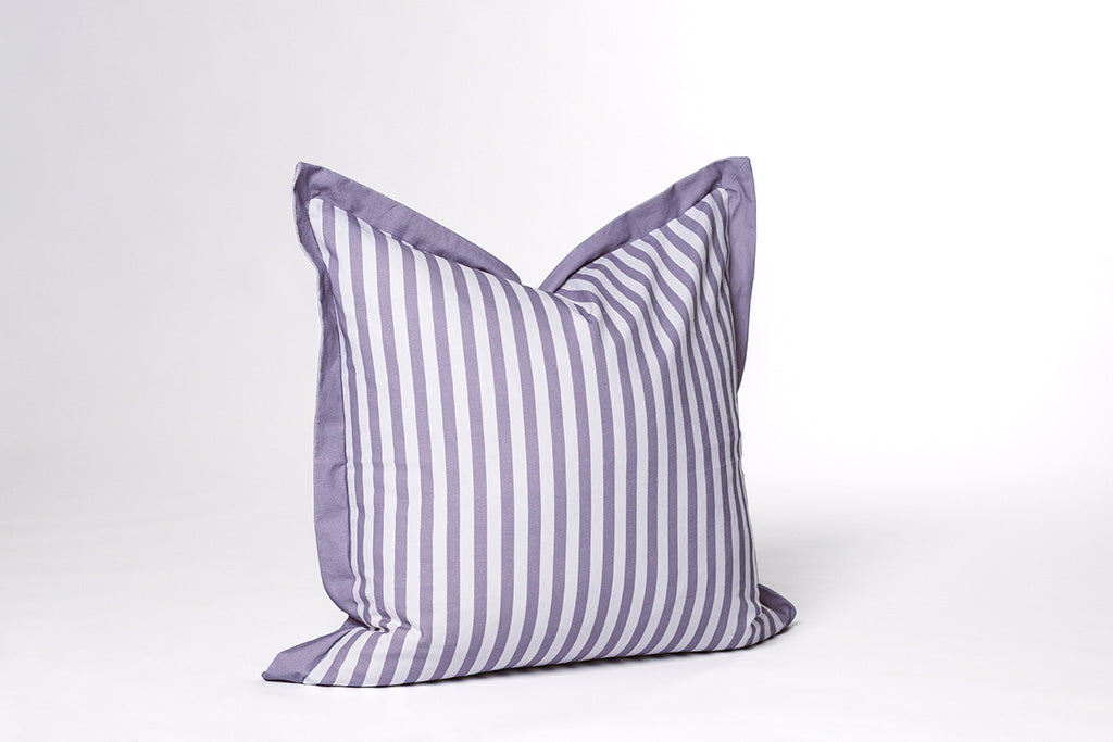 A purple and white striped pillow on a white backdrop