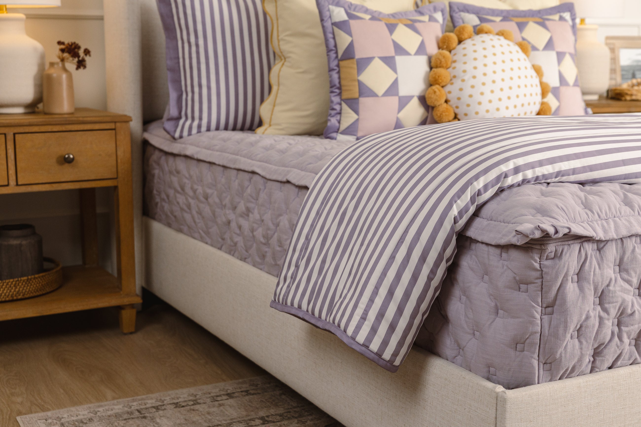 A purple bed made with purple, yellow, and white accessories. 