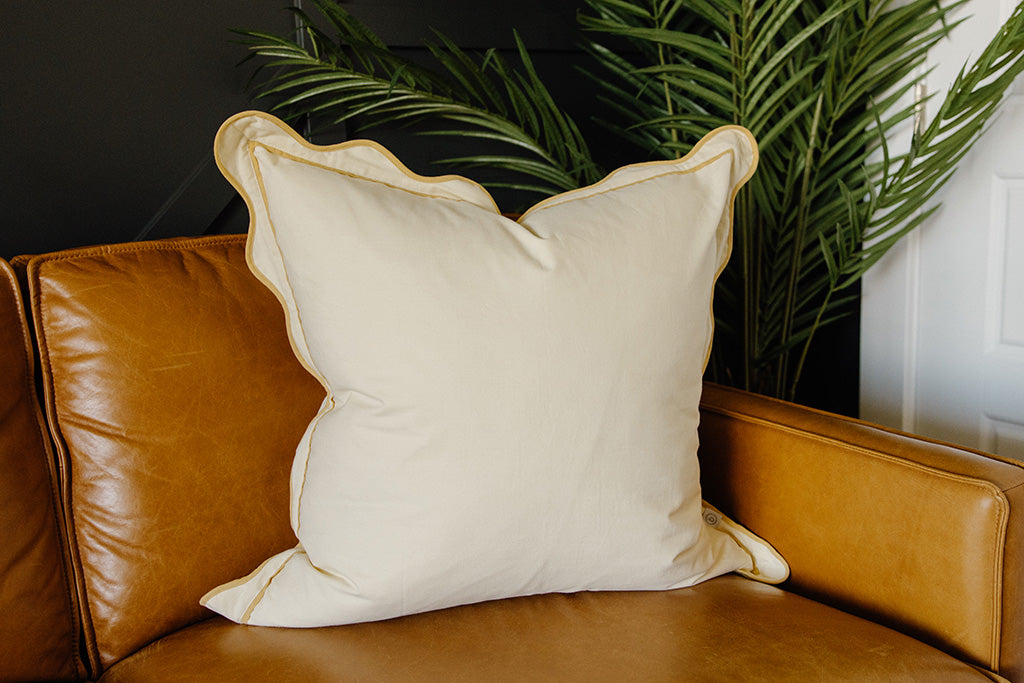 A buttercream pillow on an orange leather couch.