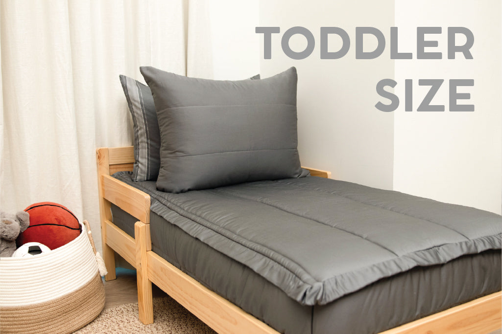 A toddler bed made with gray zipper bedding.