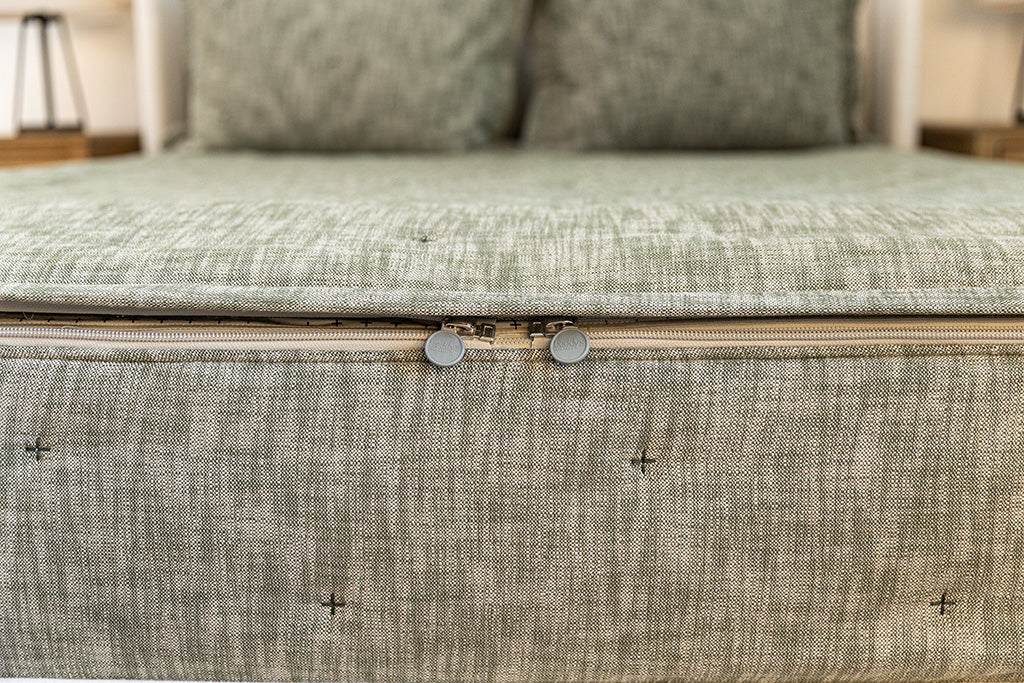 The foot of a bed made with deep emerald green zipper bedding showing where the two zippers are located.