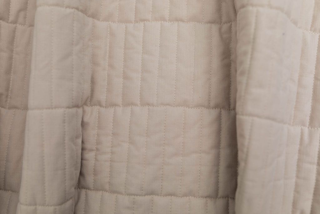 Close up of a tan blanket with keyboard stitching