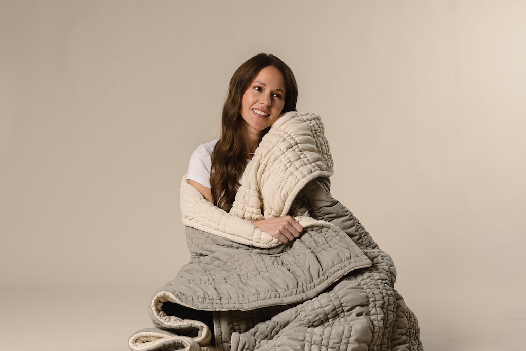 A model wrapped in a sage green and cream scrunched blanket. 