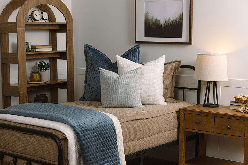 Twin bed with tan woven zipper bedding with blue and white accessories.
