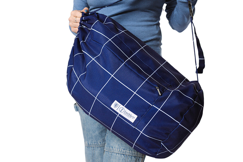 A woman holding a blue bag with white grid stripe on a white backdrop.