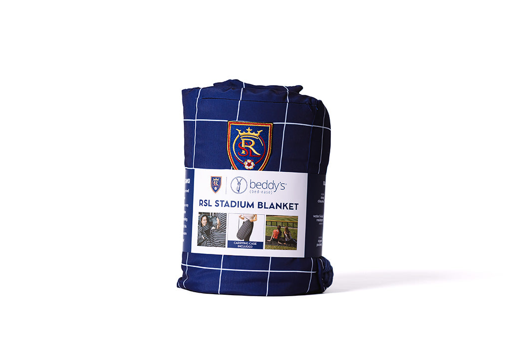 A blue blanket with white grid stripe and a RSL soccer logo on a white backdrop.
