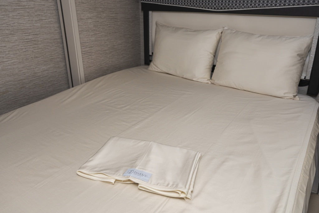 A bed made in an RV with cream zipper sheet bedding.