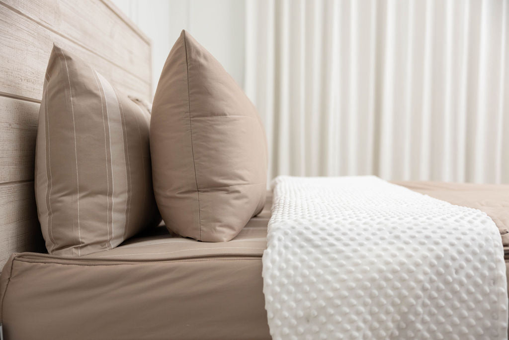 A side view of a tan zipper bedding on a bed with the top unzipped halfway down revealing the minky comfort interior. 