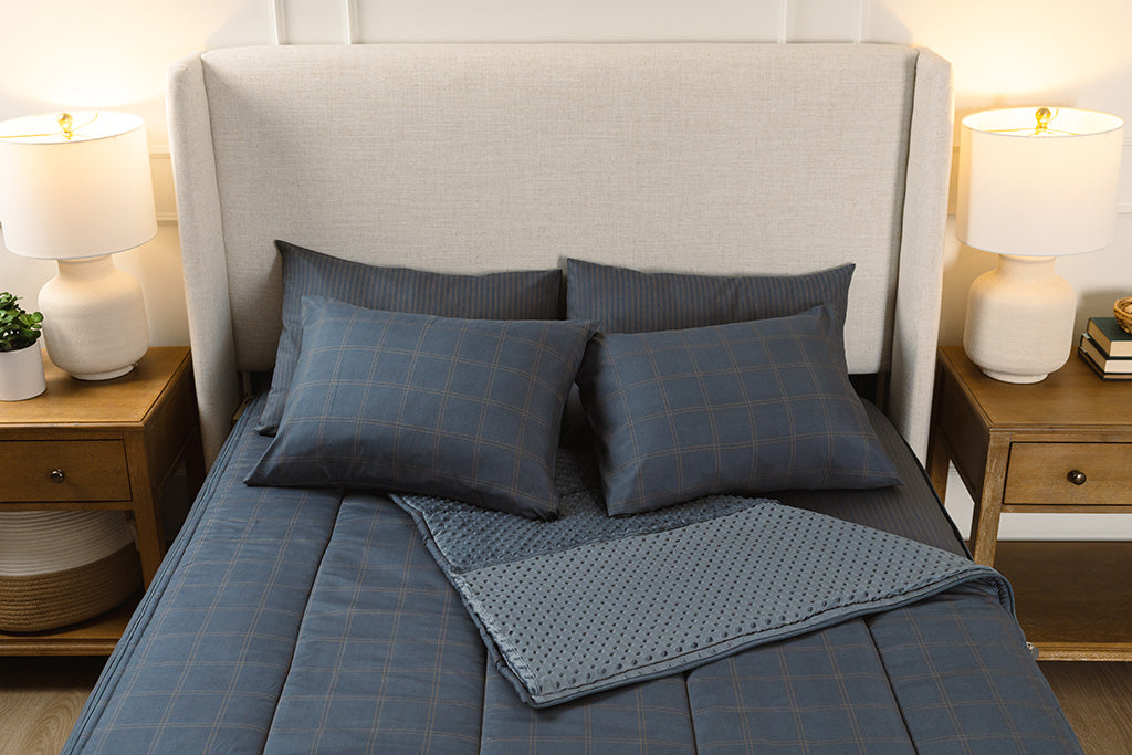 Overhead photo of slate blue grid zipper bedding with blue striped bed sheets and blue bubble minky interior.