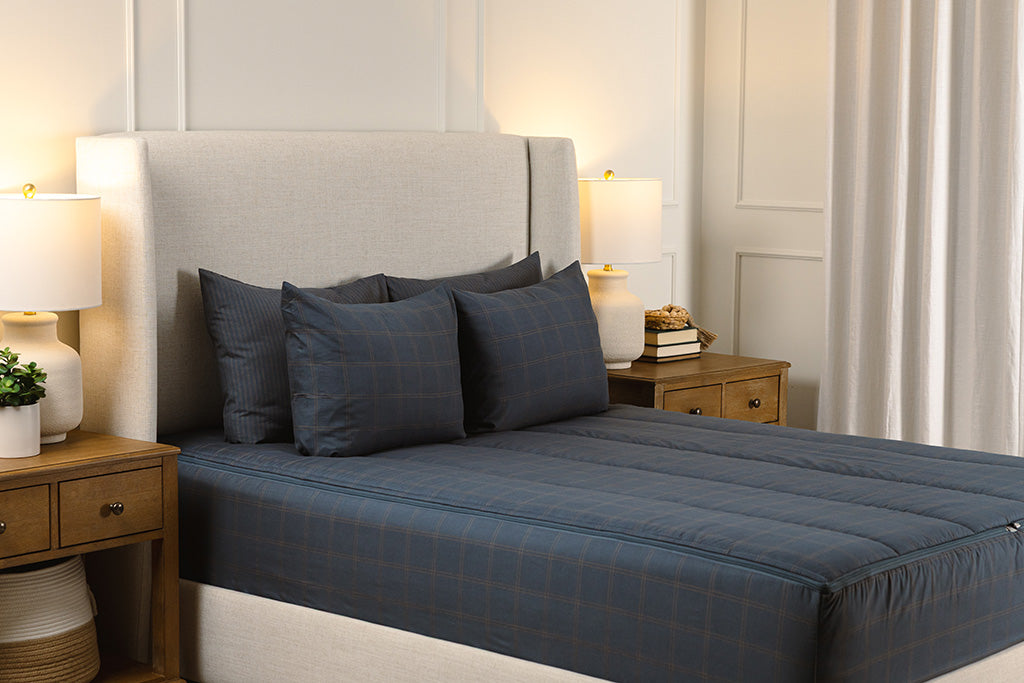 Zipper bedding on a queen, cream colored bed frame that has a slate blue grid print.