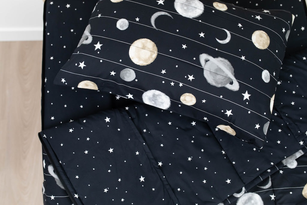 A twin bed made with black plants and stars kids zipper bedding, the top unzipped and slightly pulled back and a pillow on the bed.