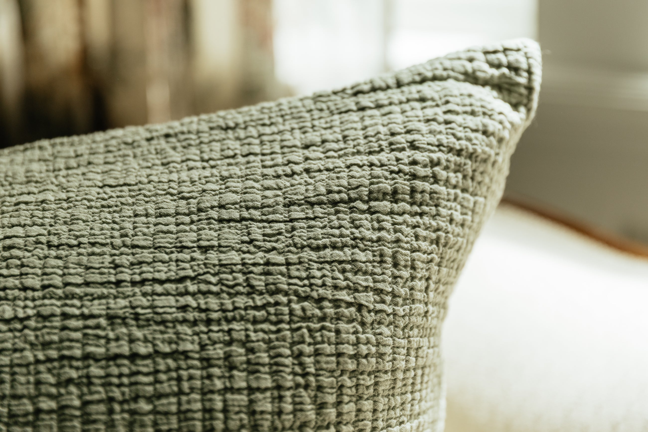 A close up view of a sage green crinckle textured euro pillow.