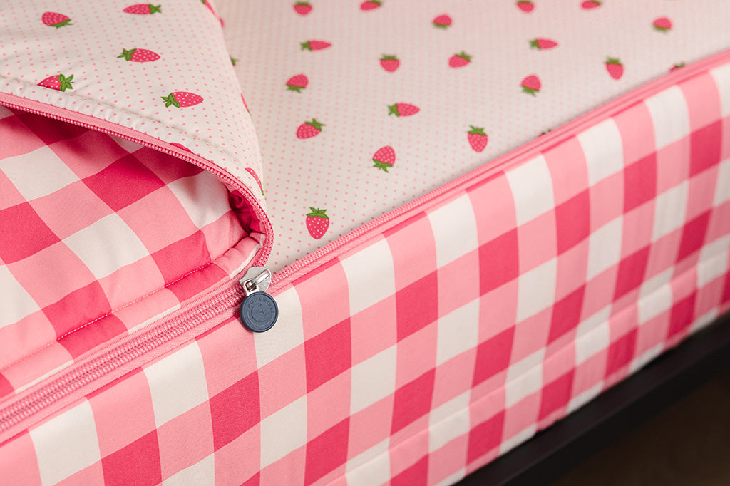 A tight shot of the zipper feature on a set of pink gingham and strawberry printed zipper bedding.