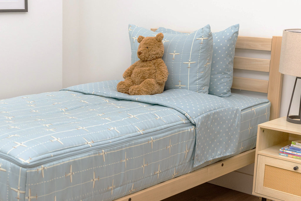 bedroom with twin bed decorated with light blue zipper bedding and airplane design with toys on the ground