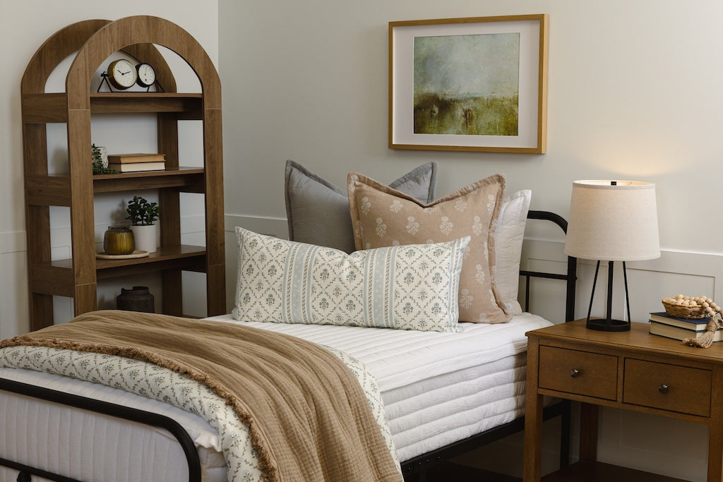 Twin bed with white quilt zipper bedding with tan, gray, and floral accessories.
