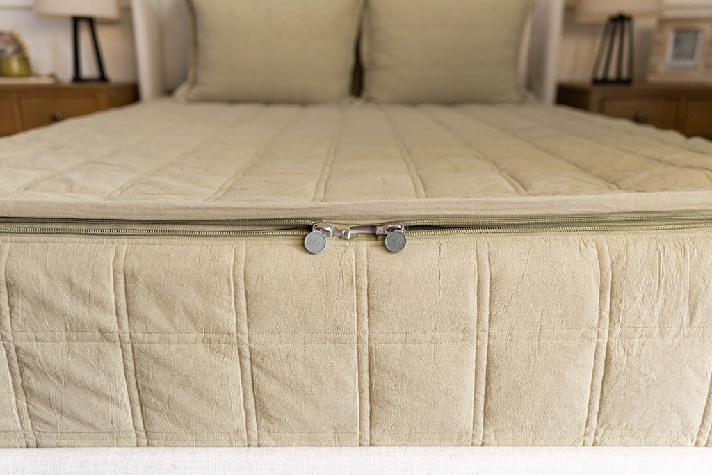 The foot of a bed made with green zipper bedding, the focus on the zipper feature of the bed.