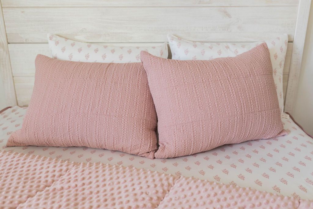 White pillowcases and pink shams on a pink zipper bedding with the comforter pulled back showing minky inner lining 