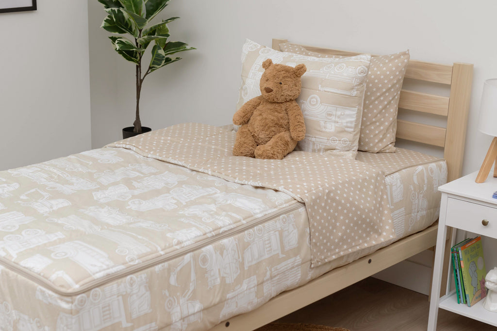 A twin bed made with light tan cars kids zipper bedding, a nightstand beside it with books on the shelf and toys scattered on the floor.